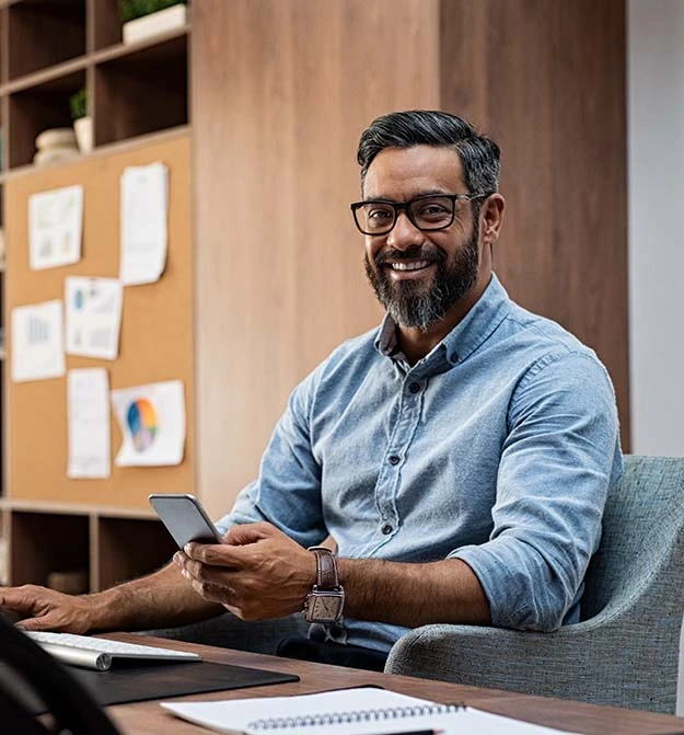 Women Smiling Whilst Sat At Desk, Approving Payments With Business Central In The Cloud